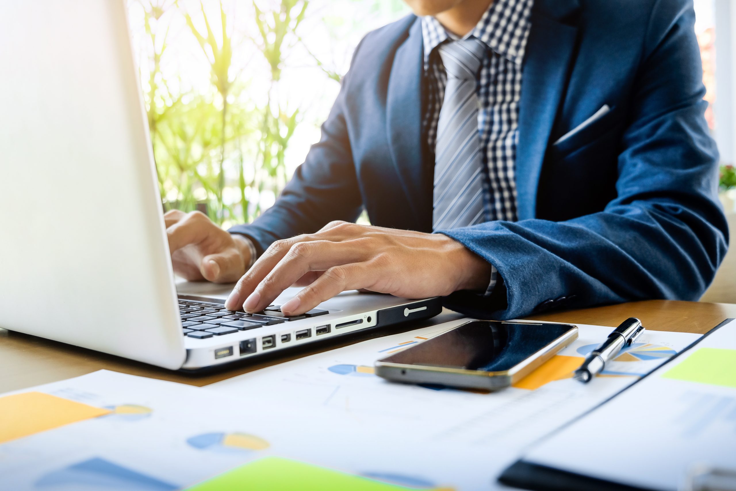 homem-de-negocios-que-trabalha-no-escritorio-com-documentos-de-dados-de-laptop-tablet-e-graficos-em-sua-mesa